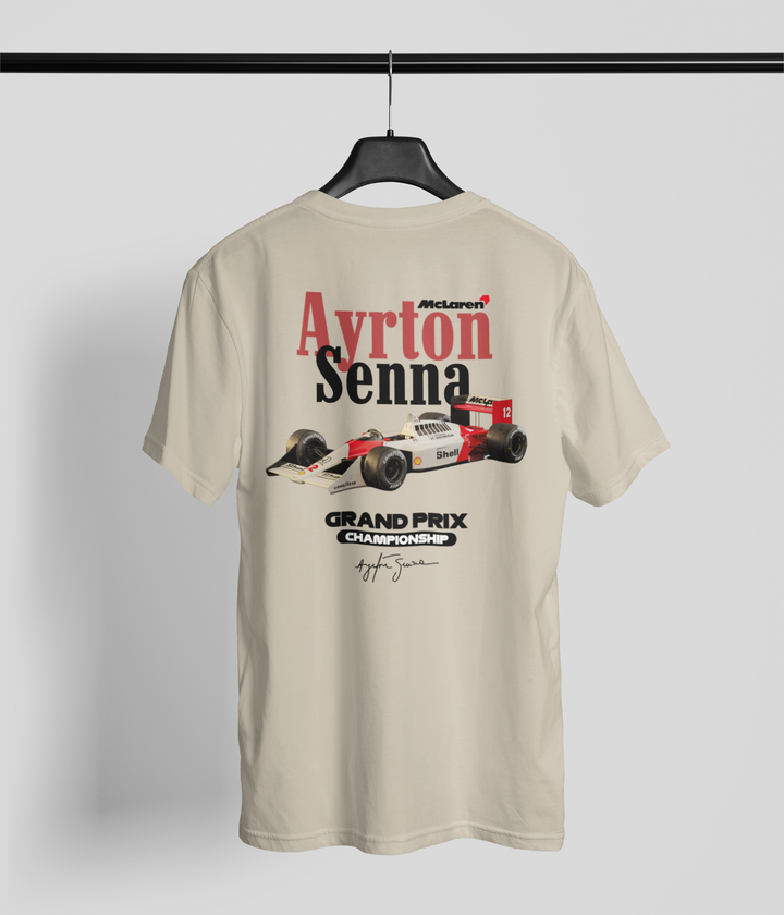 Beige t-shirt with Ayrton Senna graphic on a hanger against a gray background
